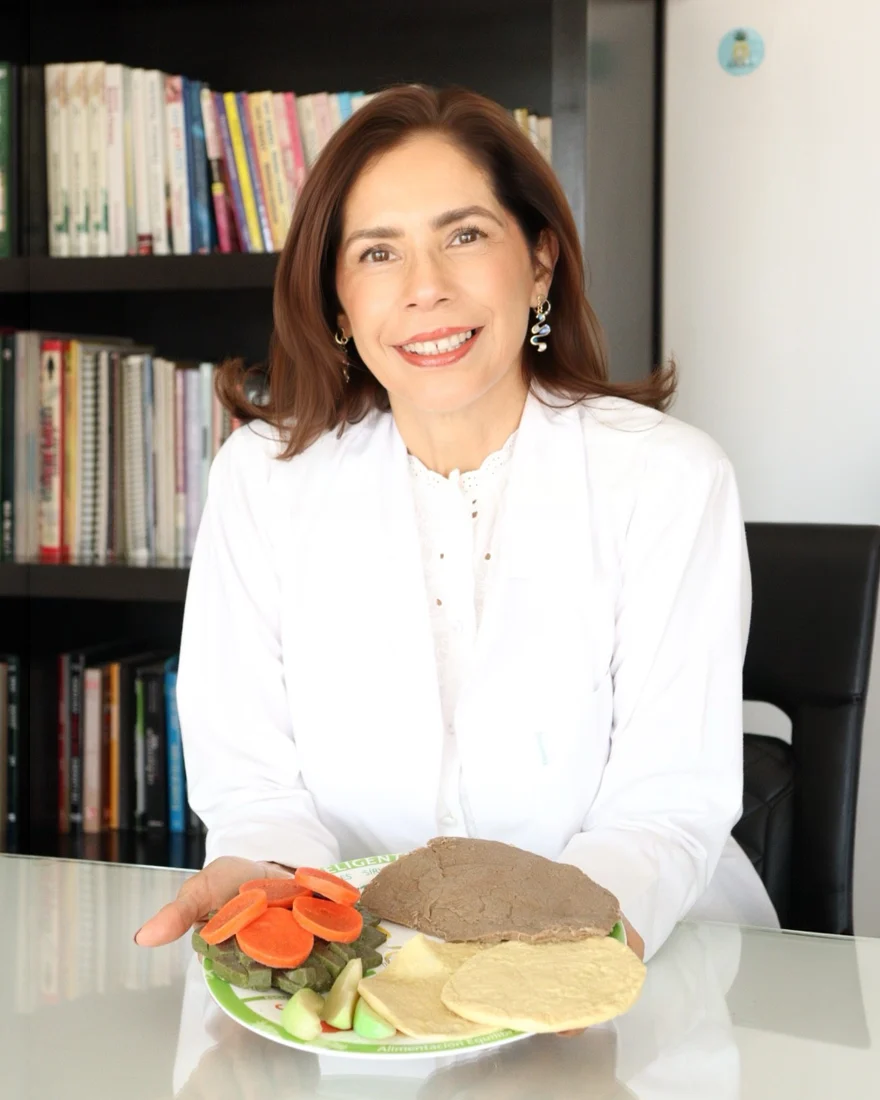 Claudia Ramos en su consultorio con un plato de alimentación equilibrada